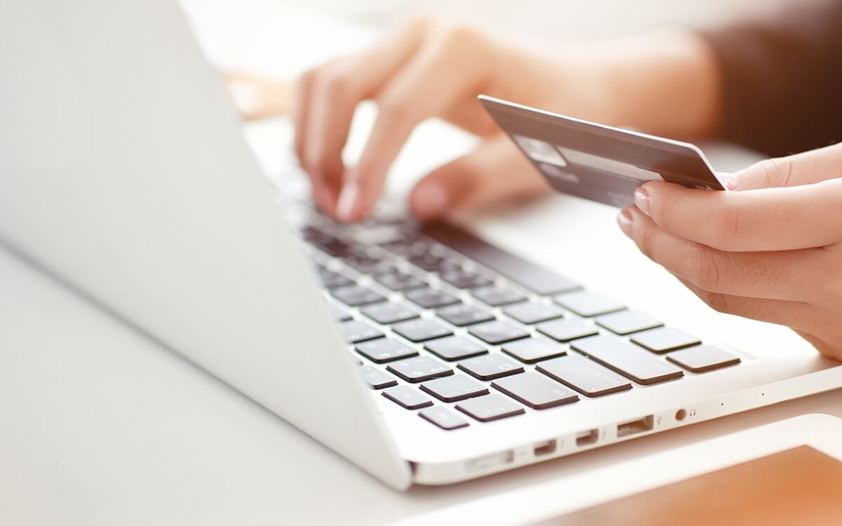 Eine Frau tippt Kreditkartendaten in einen Laptop ein